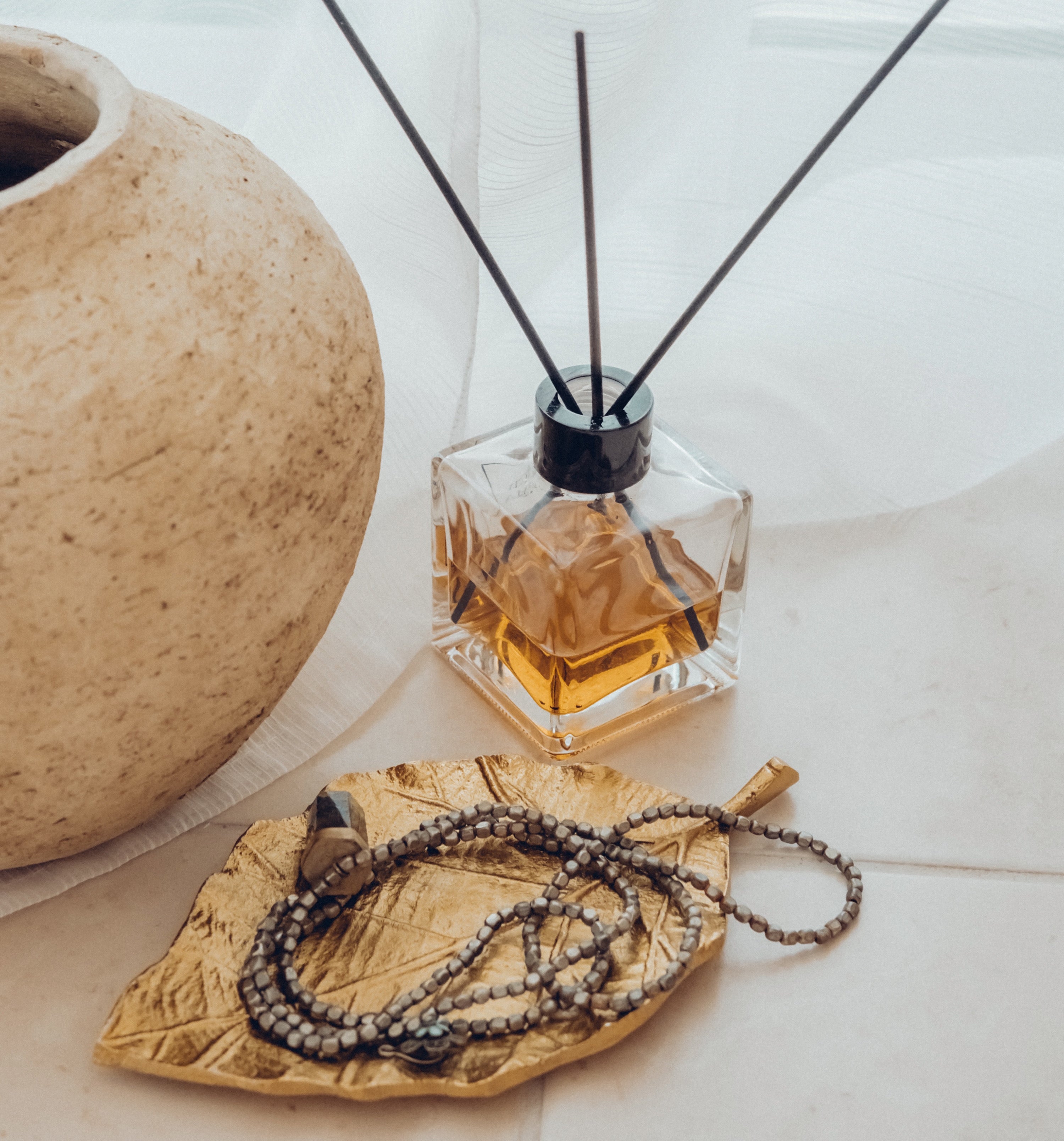 Home fragrance diffuser and a natural bead necklace. Illustration for how to safely wear scented jewelry.